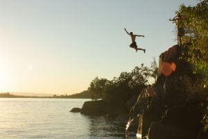 Figure jumping from a cliff into water